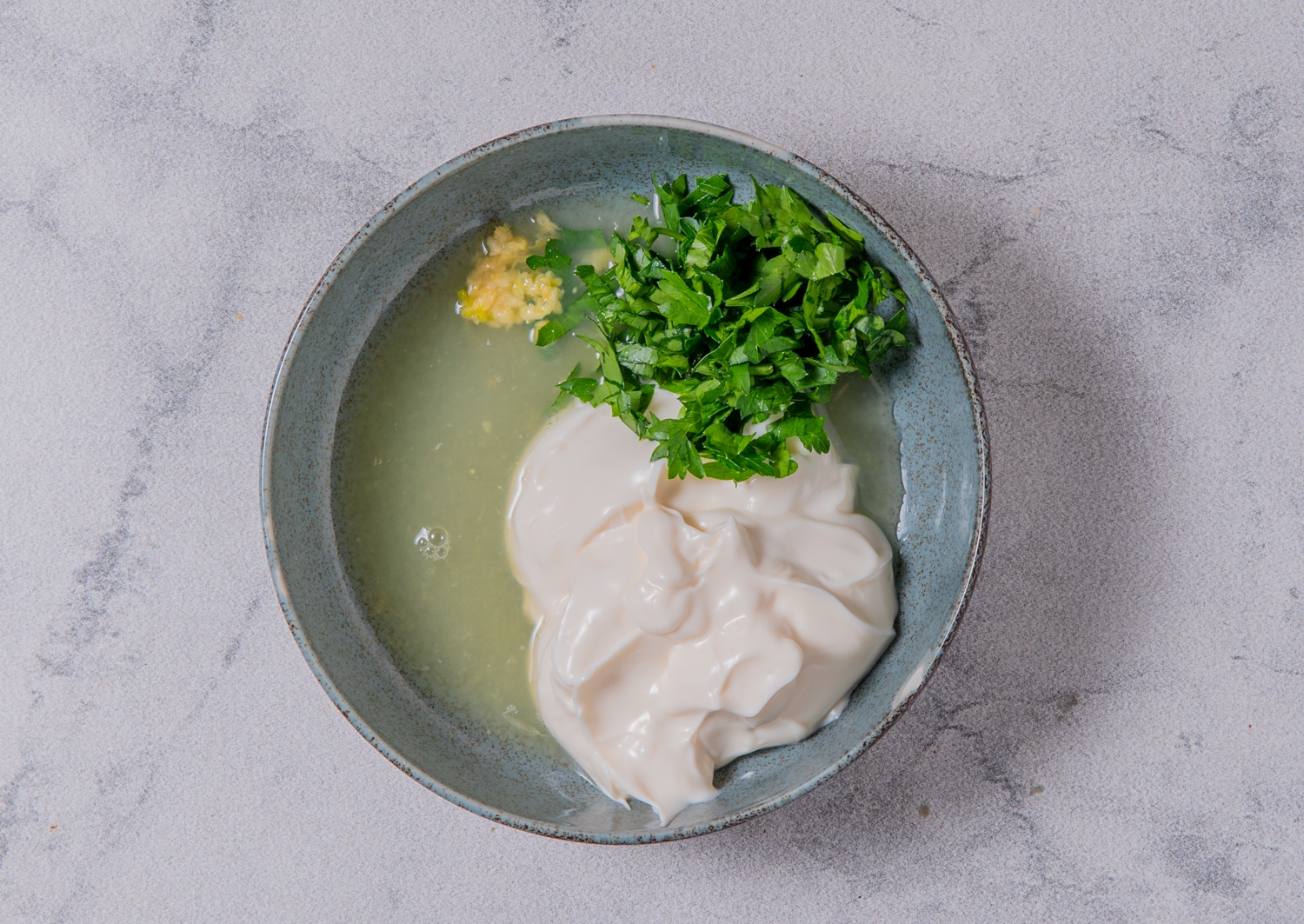Mayonnaise, lemon juice, minced garlic, and chopped parsley in a bowl to prepare lemon garlic dipping sauce